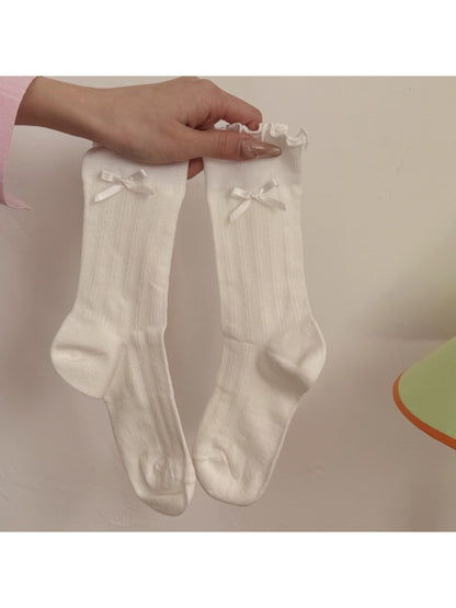 Rufia socks styled with a skirt, emphasizing the frill and bow accents