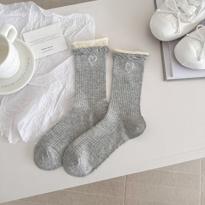 Stack of Rufia crew socks in various neutral colors folded neatly