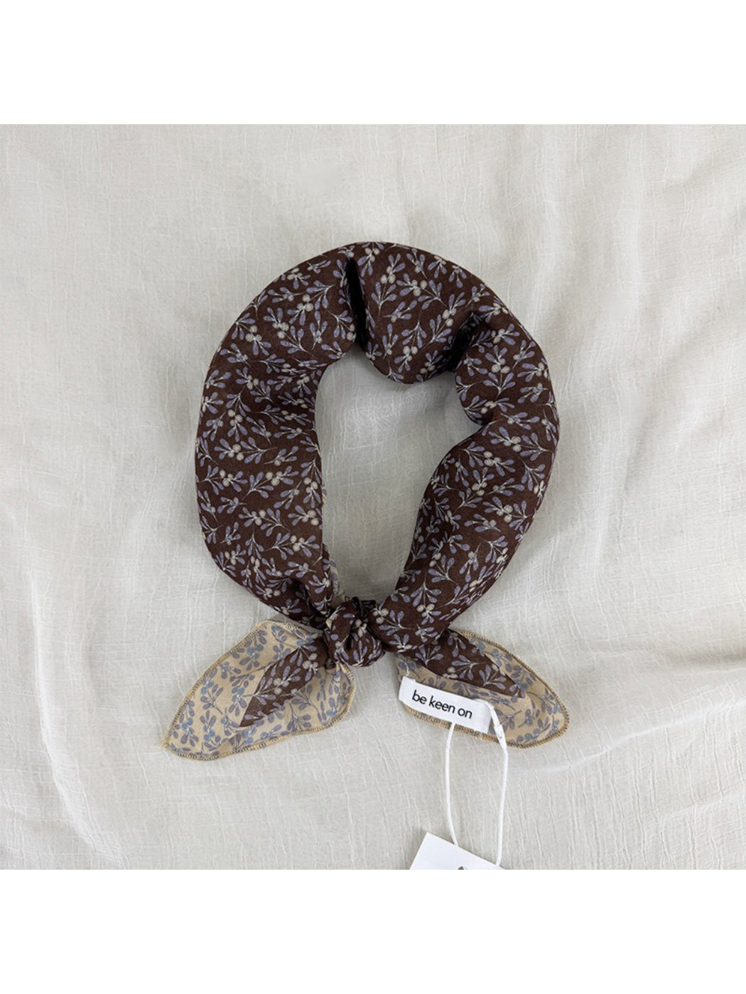 Close-up of Scarvii scarf fabric with small floral patterns and detailed border