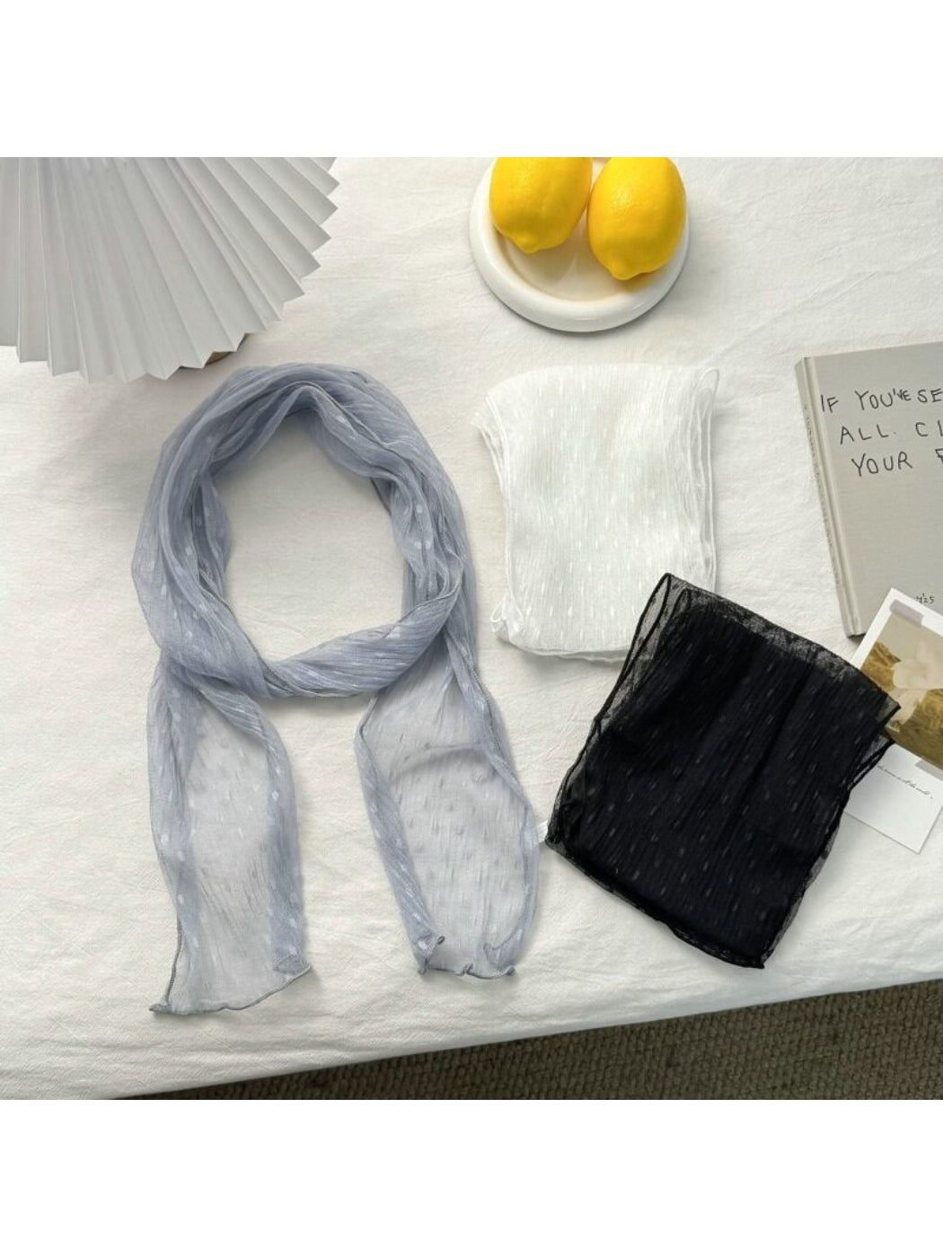 Lightweight neck scarf with white polka dots on black fabric displayed flat