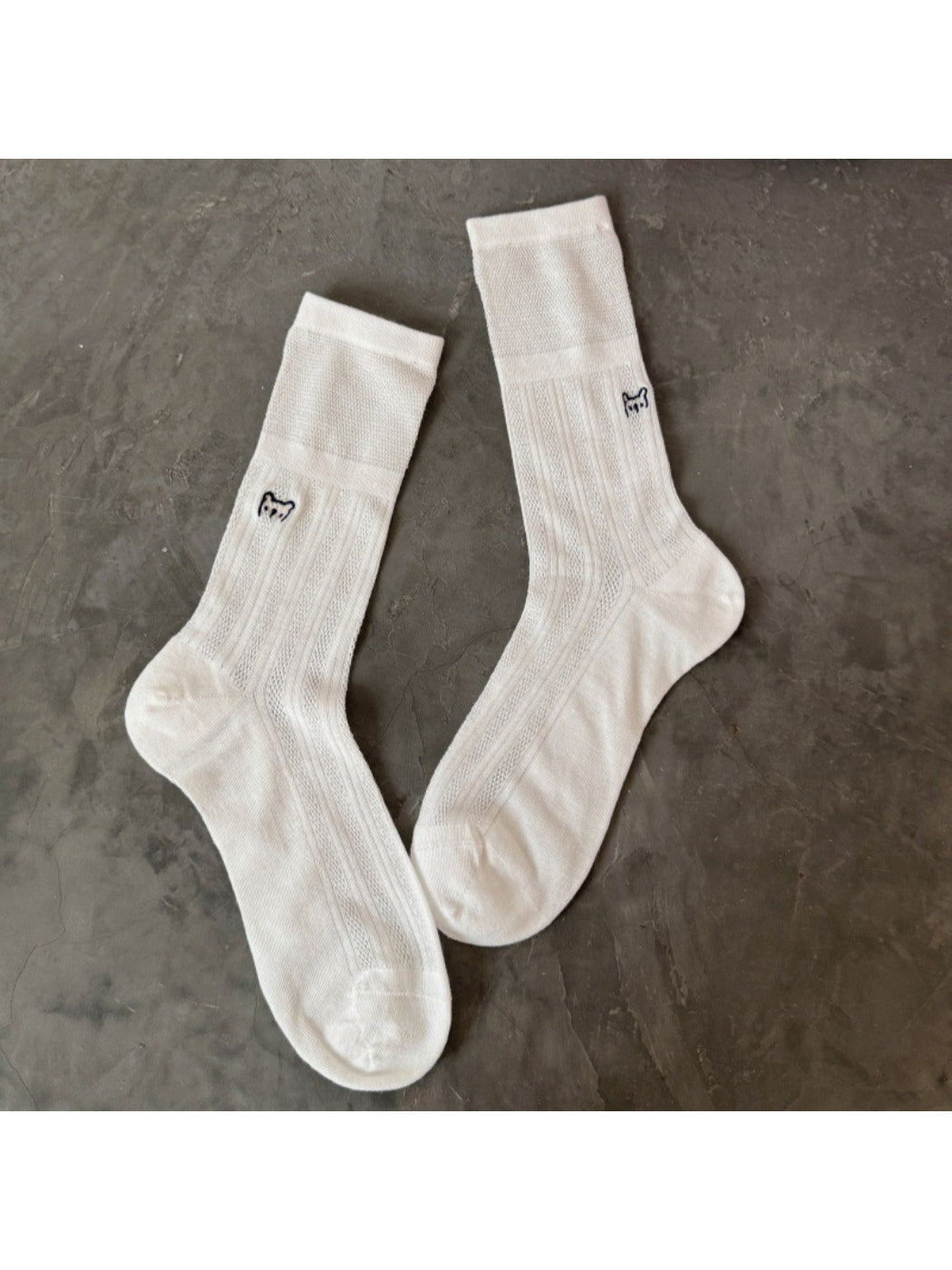 Rufia slouch socks folded with visible black cat embroidery on white fabric