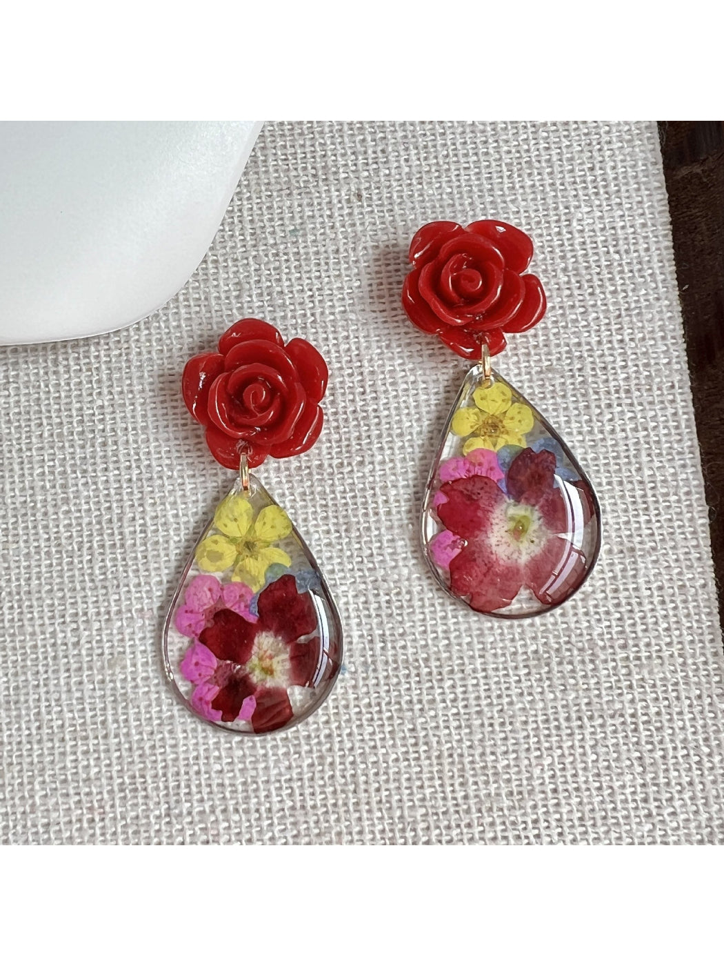 Close-up of Earwish Rose Teardrop Earrings with pink gemstone and silver setting