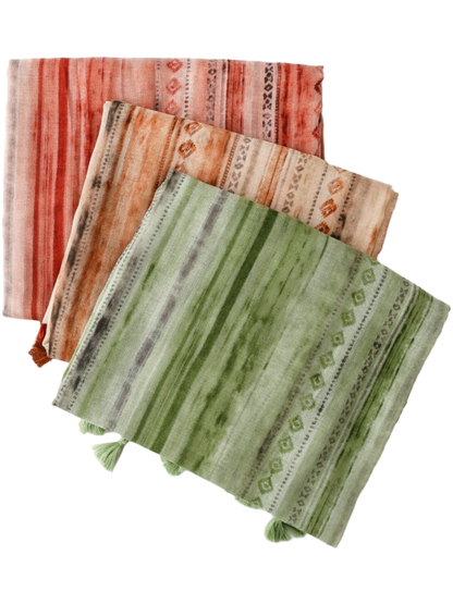 Three folded scarves with striped diamond patterns in orange red, camel and green
