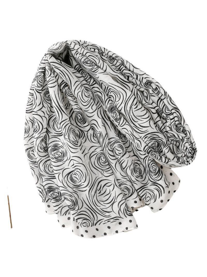 Rose-pattern scarf arranged in a loose loop with its dotted border visible