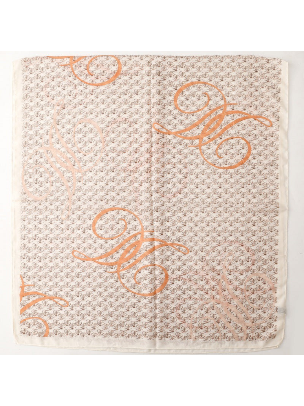 Ivory scarf spread flat, showing repeating brown motifs, oversized orange scrolls and a plain border