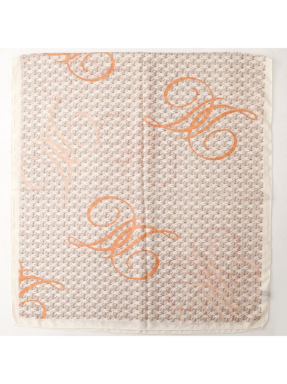 Ivory scarf spread flat, showing repeating brown motifs, oversized orange scrolls and a plain border