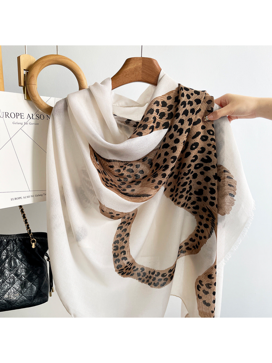 White scarf draped on a hanger, close-up of the spotted leopard motif