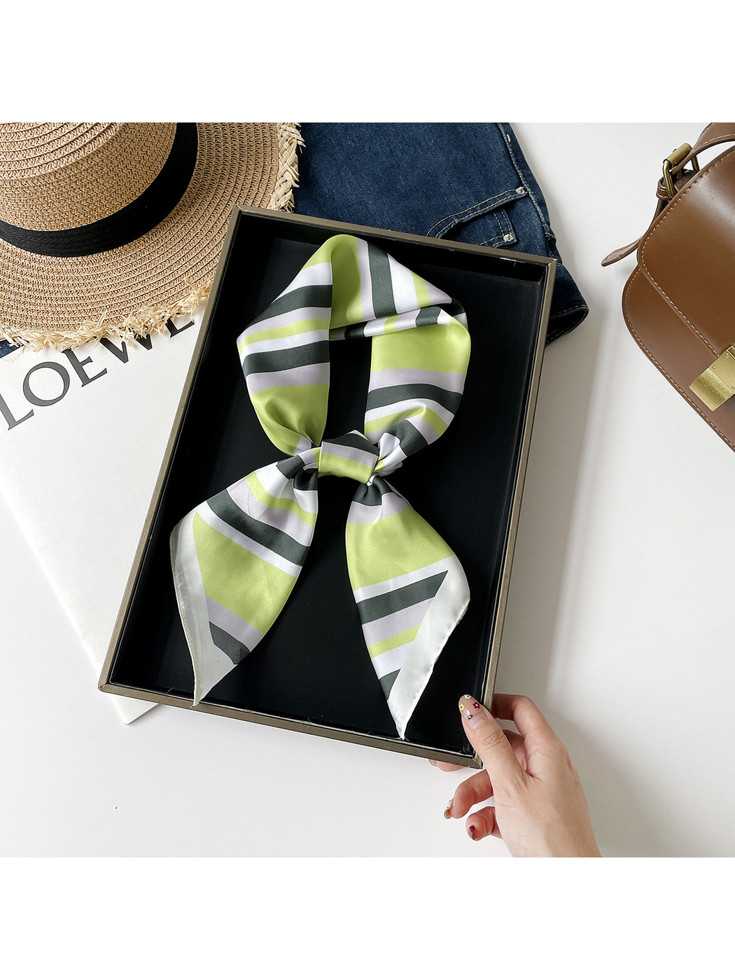 Green striped scarf arranged in a knotted loop on a black tray