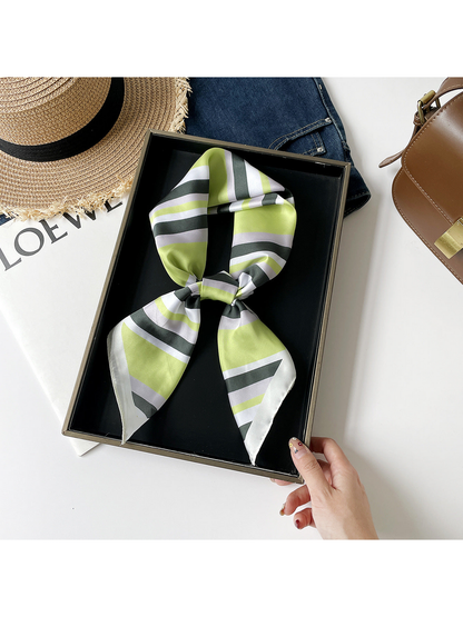 Green striped scarf arranged in a knotted loop on a black tray