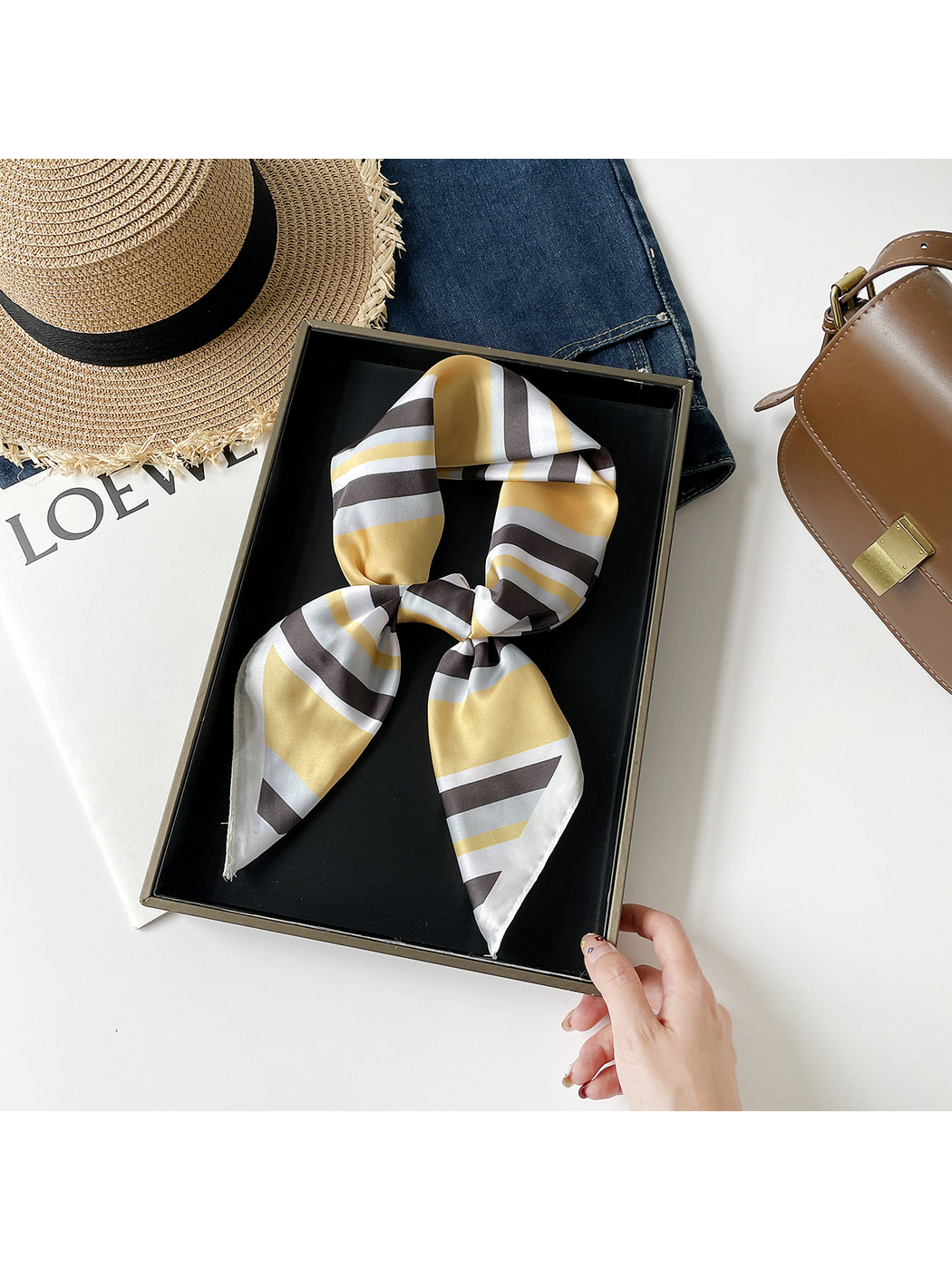 Yellow striped scarf arranged in a knotted loop on a black tray