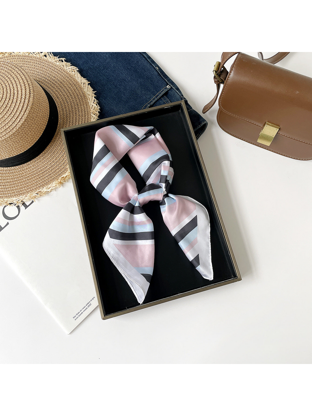 Pink striped scarf arranged in a knotted loop on a black tray