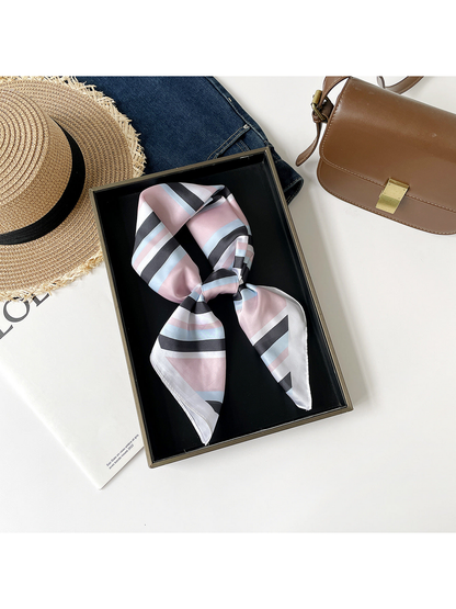 Pink striped scarf arranged in a knotted loop on a black tray