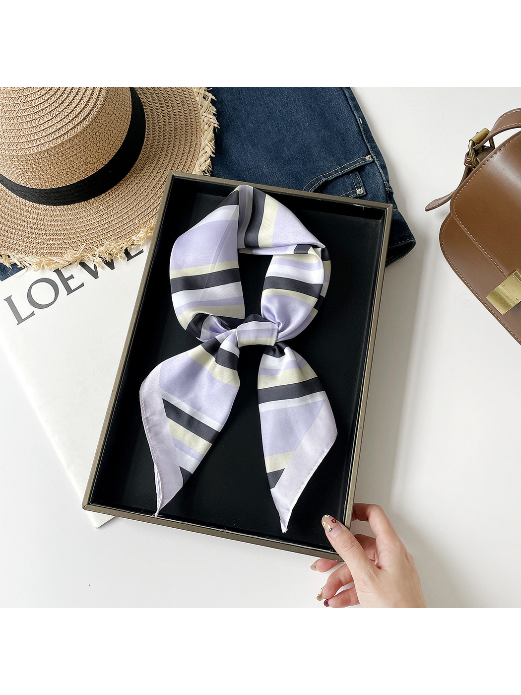 Purple striped scarf arranged in a knotted loop on a black tray