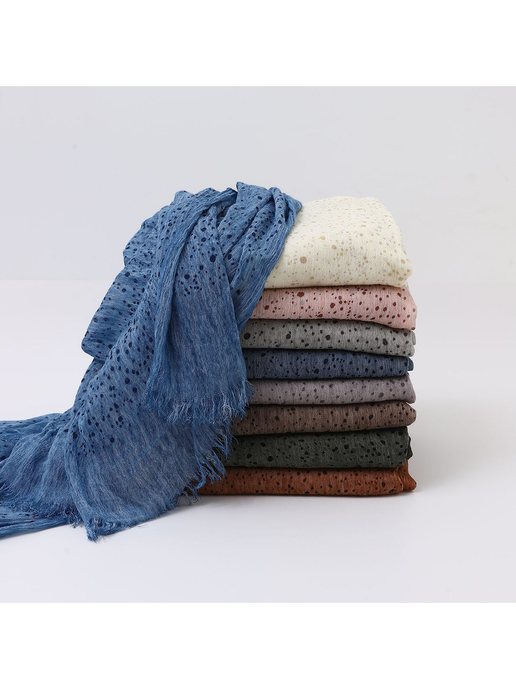 Scarves stacked in several colors with a blue scarf draped over the front