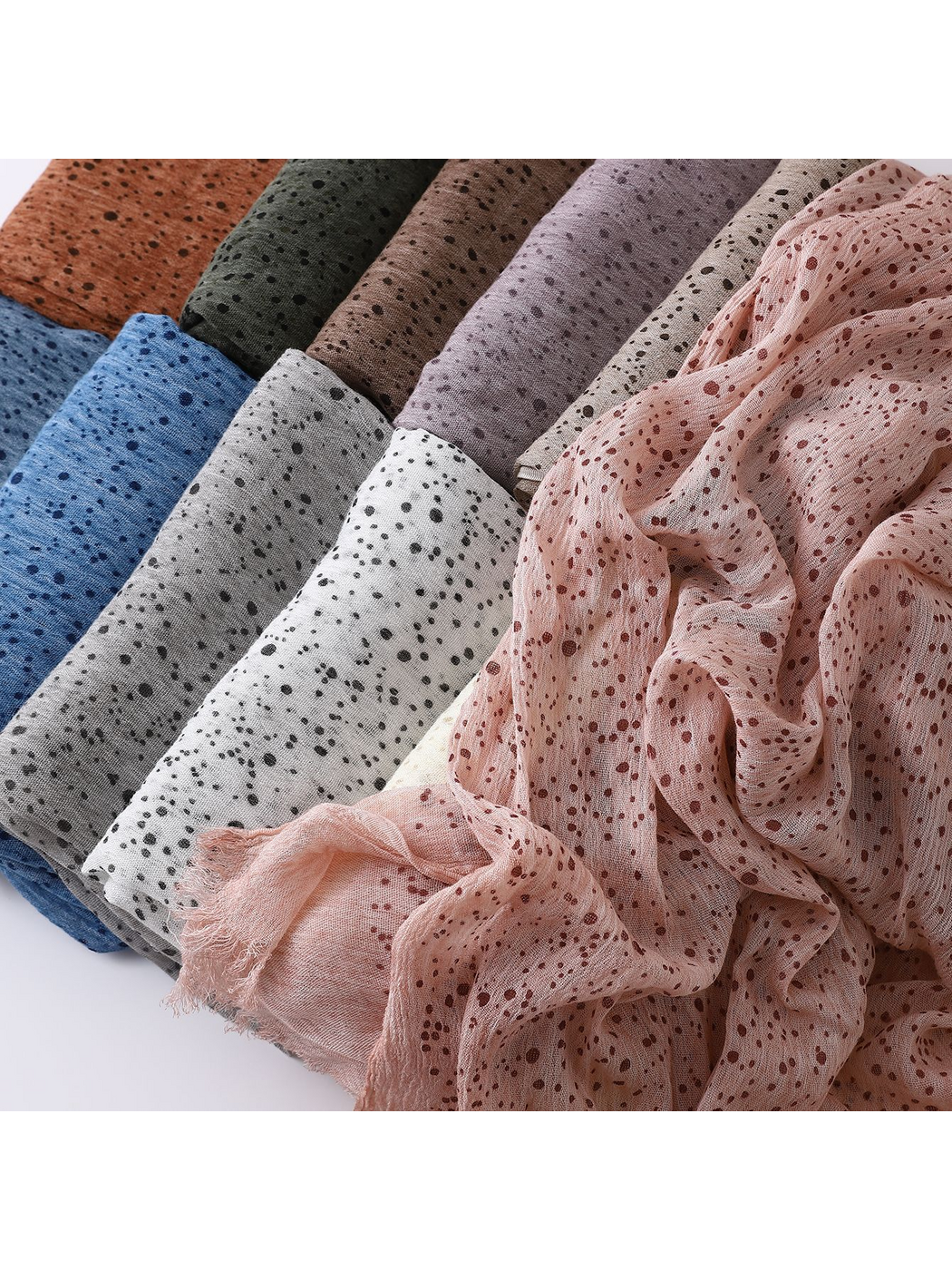 Close-up of scarves in several colors with pink fabric draped across the foreground