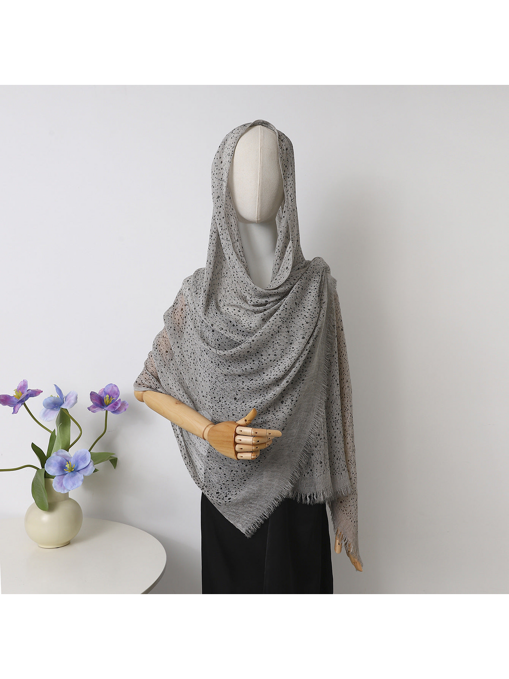 Gray openwork scarf with fringed edges draped over a mannequin