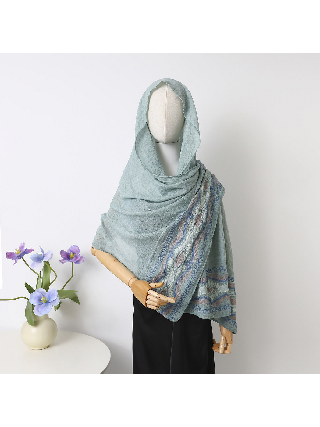 Mint scarf draped over a mannequin's head and shoulders with geometric border visible
