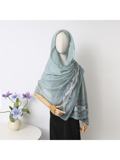 Mint scarf draped over a mannequin's head and shoulders with geometric border visible