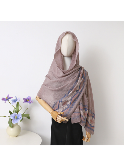 Blush scarf draped over a mannequin's head and shoulders with geometric and leafy border