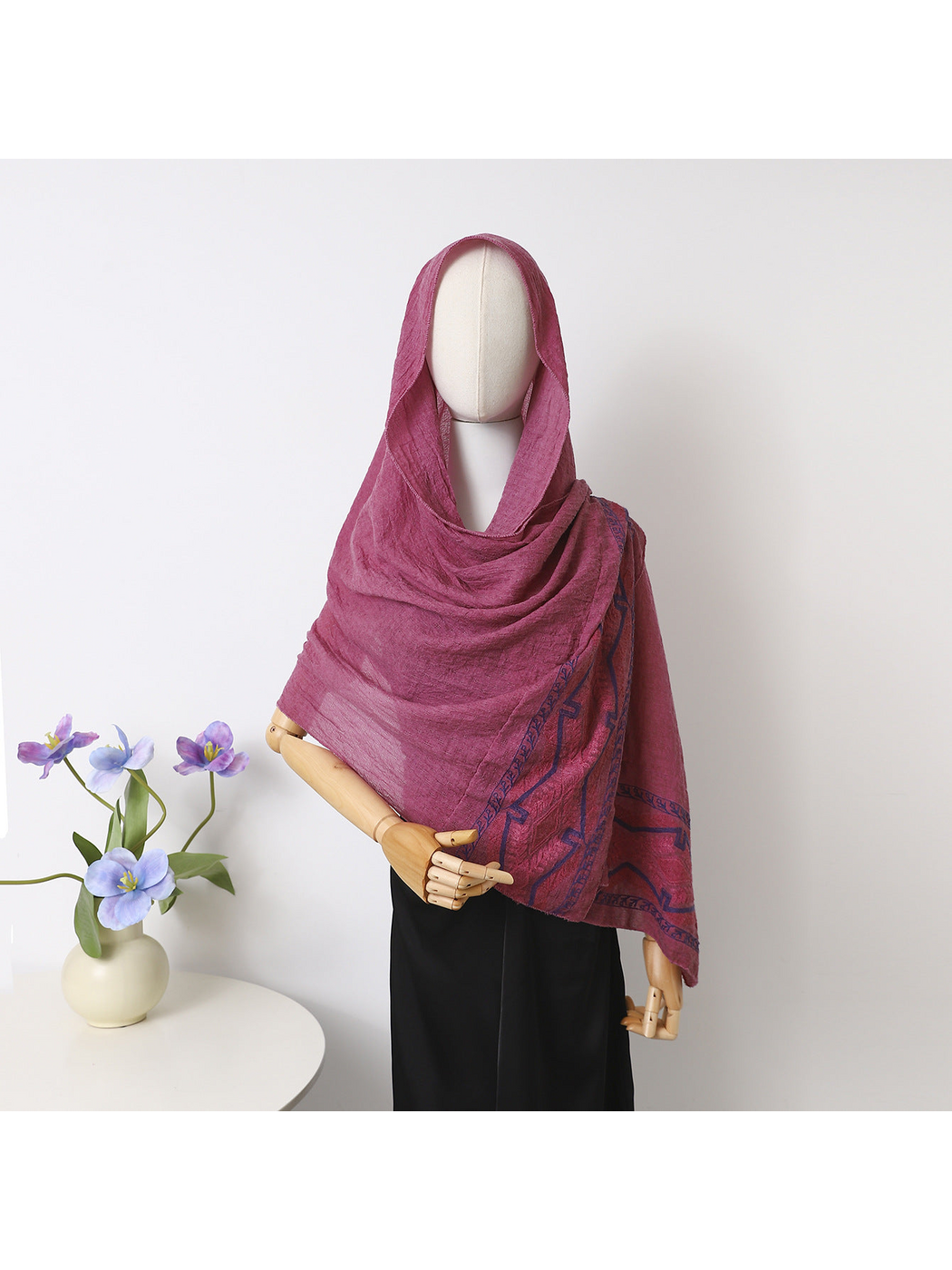 Red scarf draped over a mannequin's head and shoulders with dark blue geometric border
