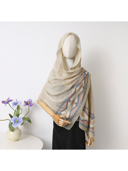 Beige scarf draped over a mannequin's head and shoulders with geometric and leafy border