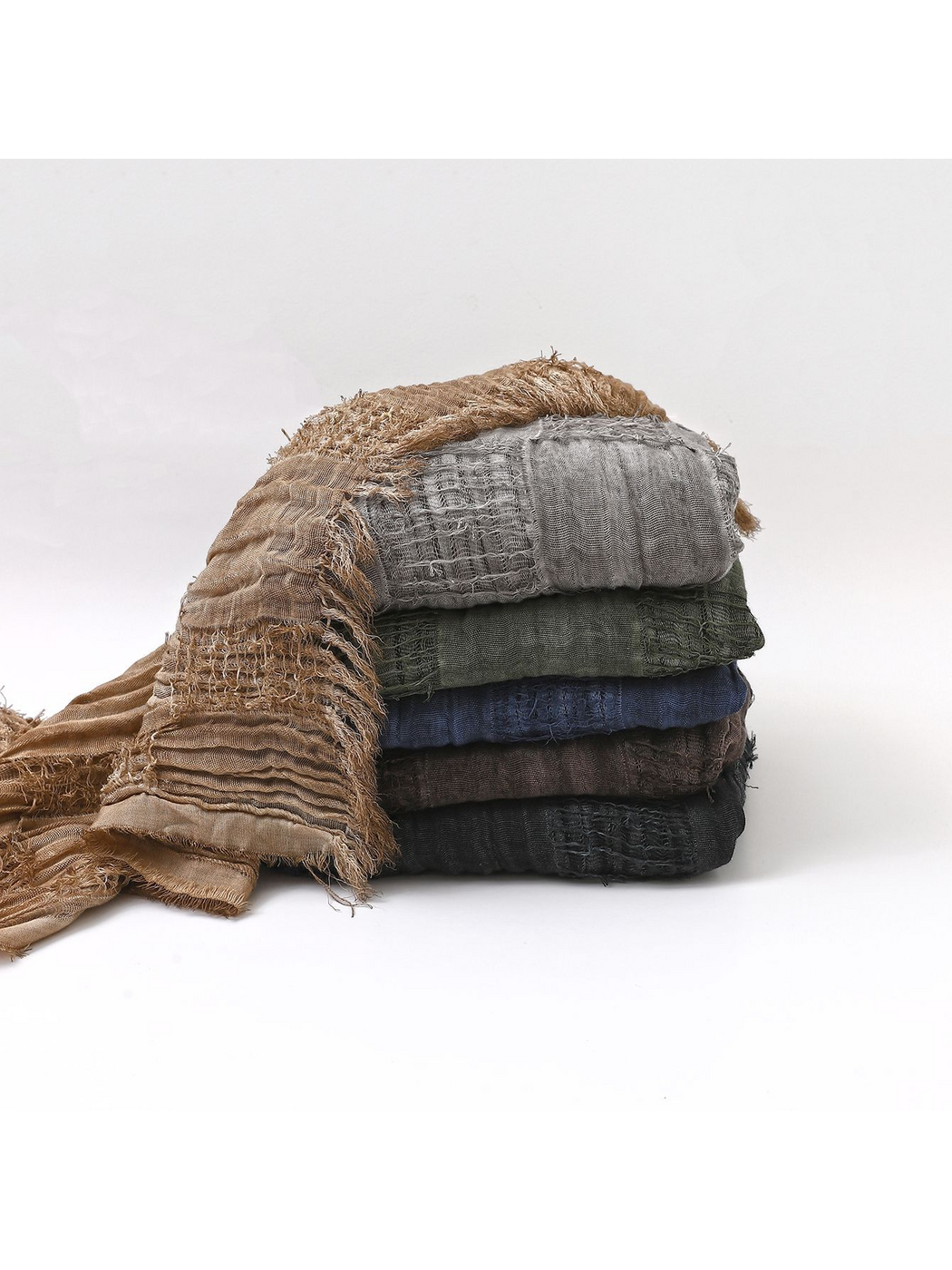 Stacked scarves in six colors showing crinkled texture, openwork bands and fringed edges