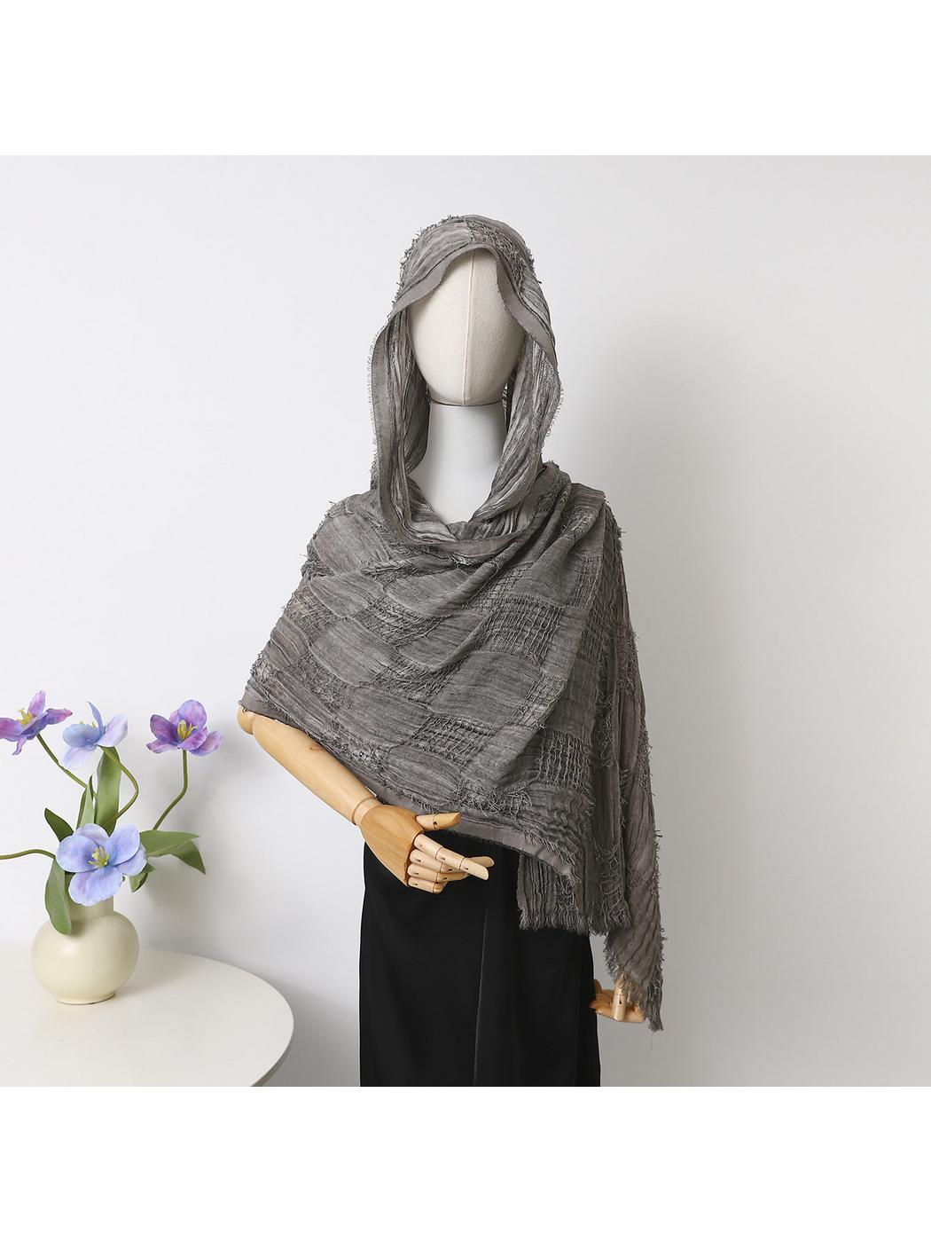 Gray scarf draped over a mannequin’s head and shoulders, showing openwork bands and fringed edges