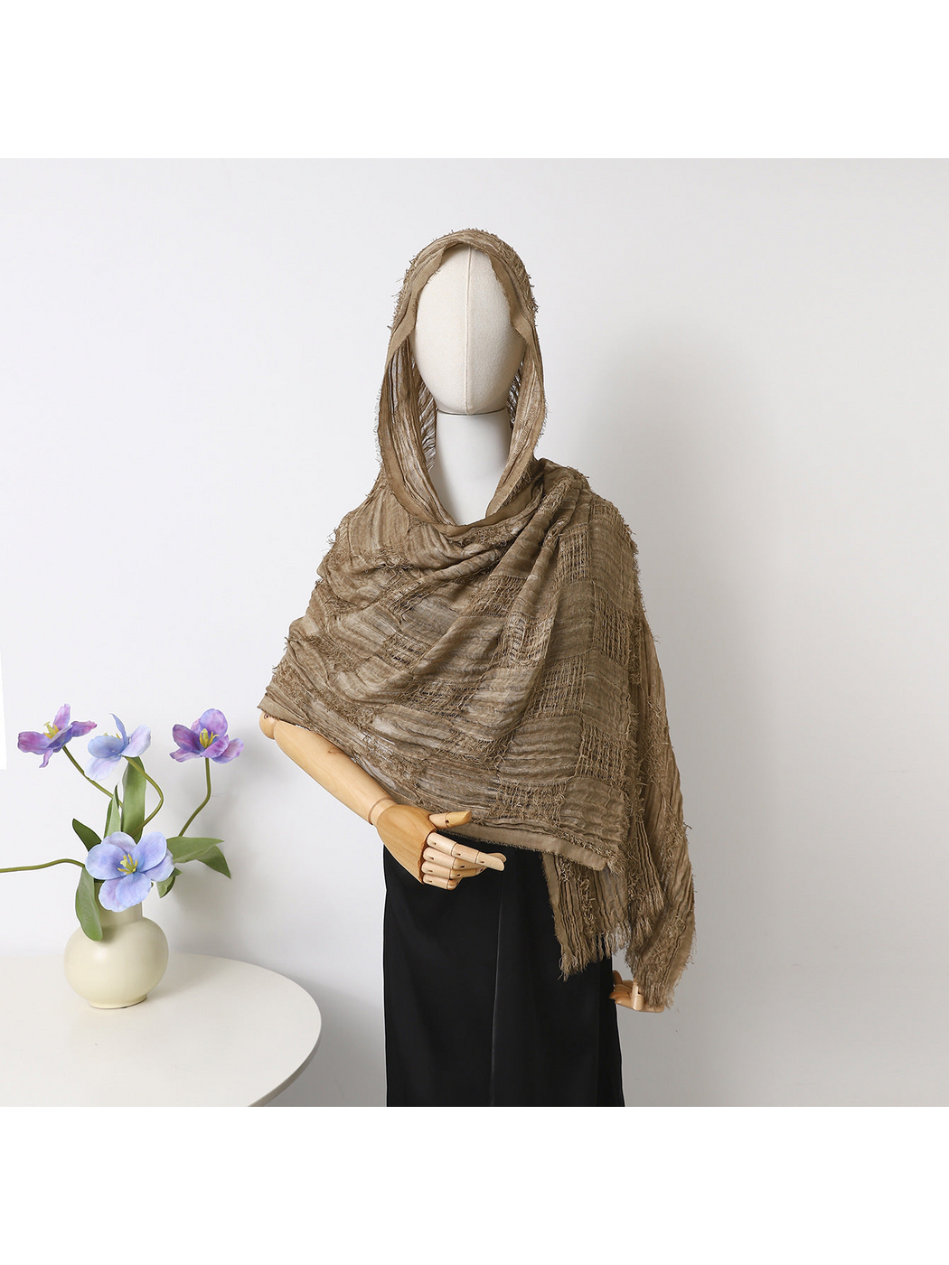 Camel scarf draped over a mannequin’s head and shoulders, showing textured bands and fringed edges