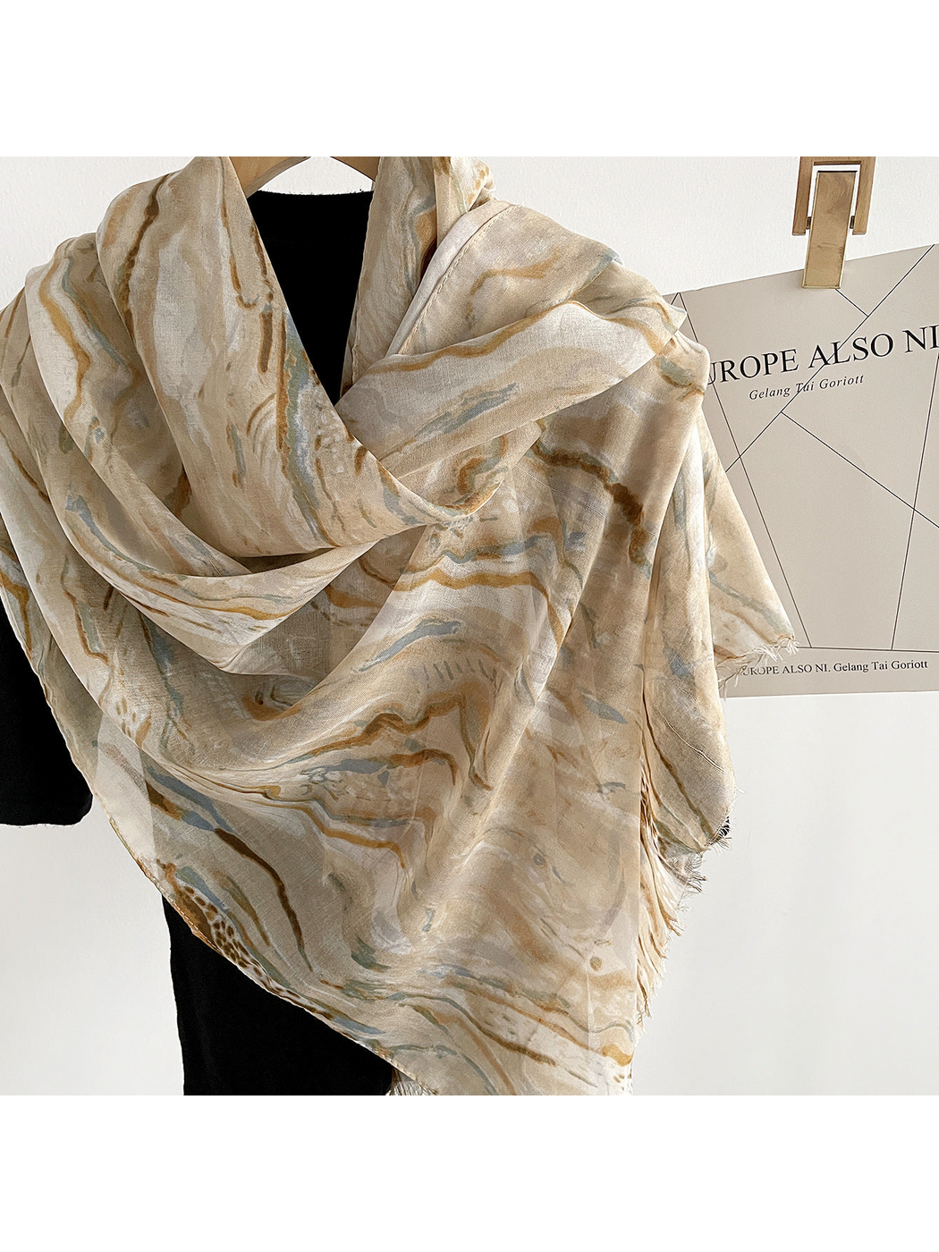 Close-up of Beige marbled scarf folds, woven texture and fringed edge
