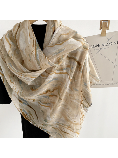 Close-up of Beige marbled scarf folds, woven texture and fringed edge