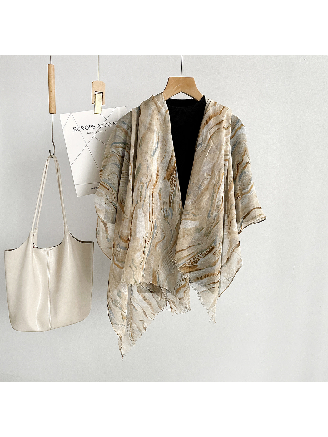 Beige marbled scarf draped open over a black top