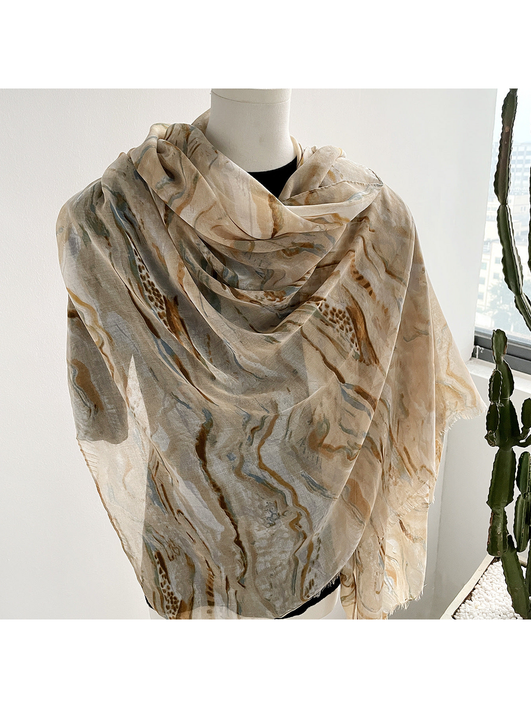 Beige marbled scarf draped around a mannequin, close-up view