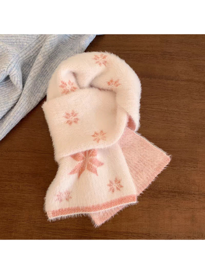Pink scarf with snowflake motifs and contrasting border, looped on a wooden table