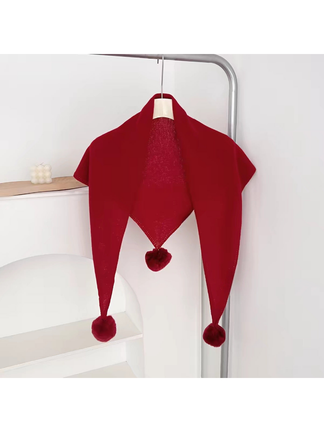 Red knit triangle scarf hanging open with three pom-poms
