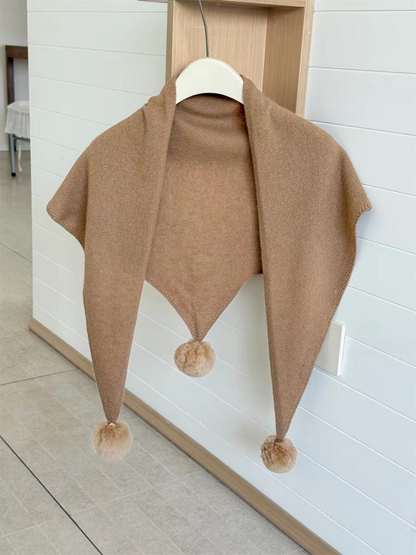 Camel knit triangle scarf hanging open with three pom-poms