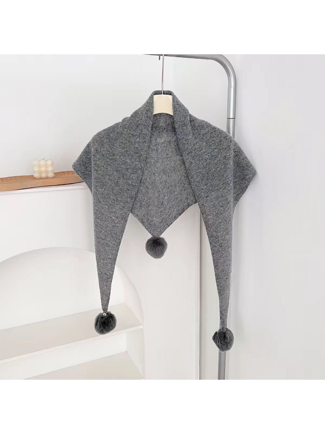Gray knit triangle scarf hanging open with three pom-poms