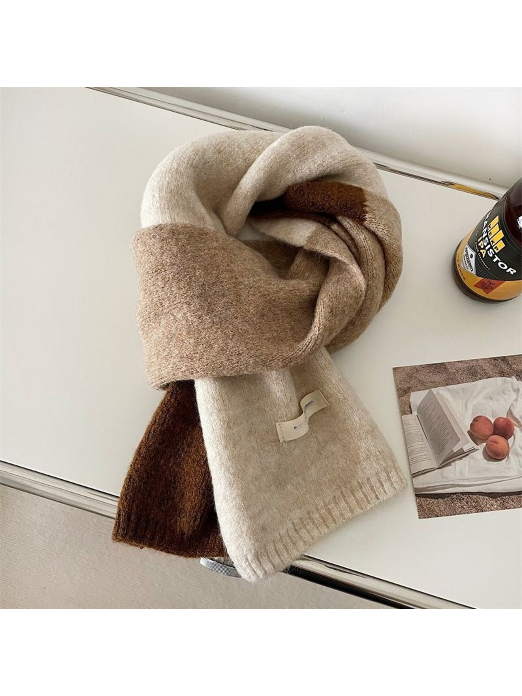 Beige color-block scarf with brown sections and ribbed ends, looped on a tabletop