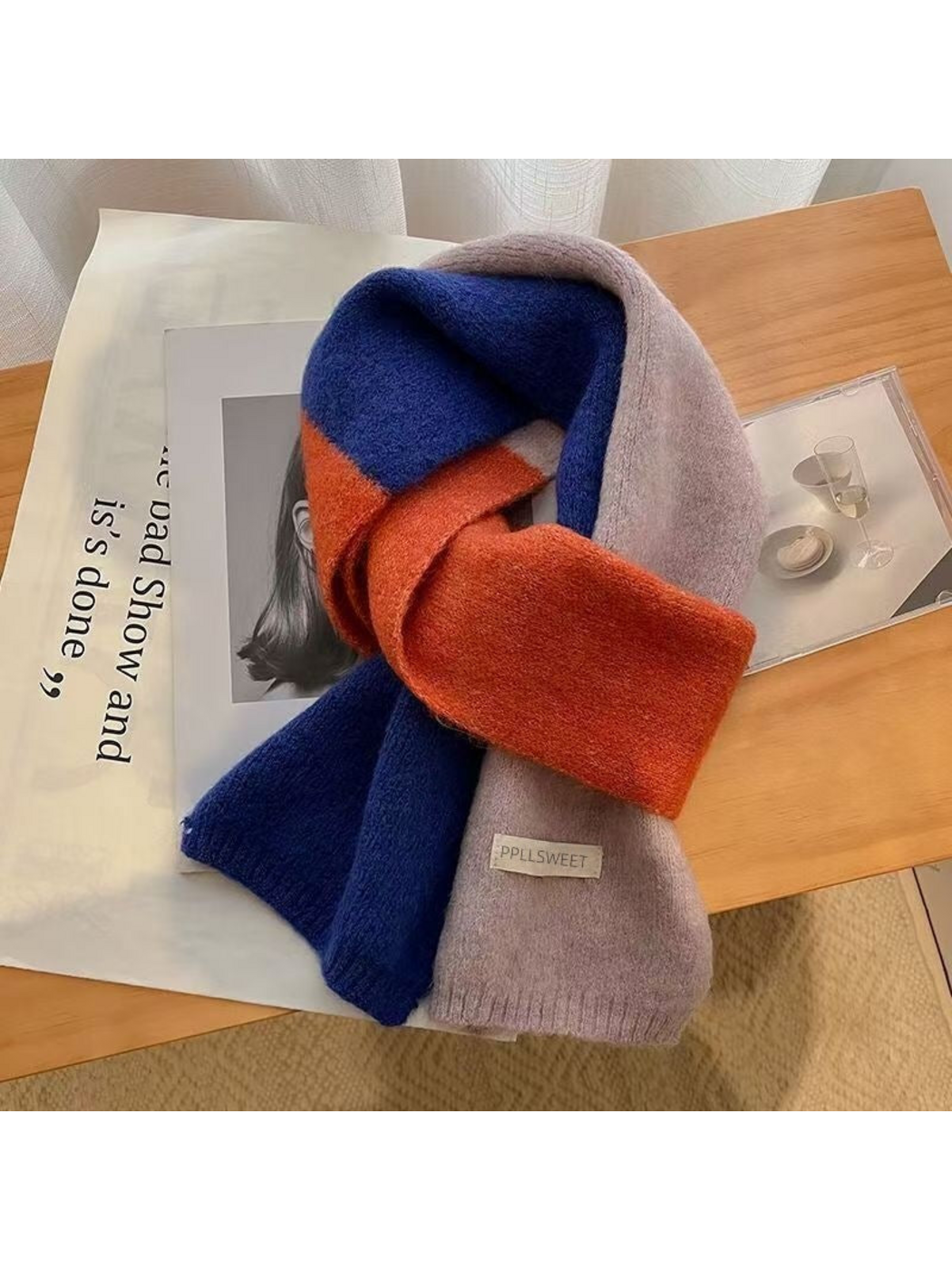 Blue color-block scarf with orange and purple sections, looped on a wooden table
