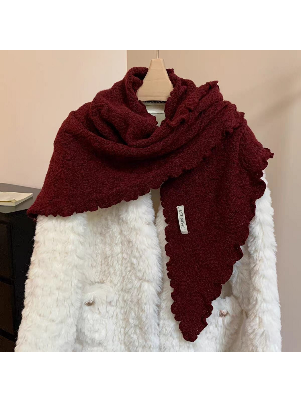 Burgundy triangle scarf with scalloped edges draped over a white coat
