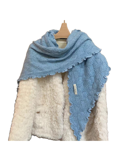Blue scarf with openwork knit and scalloped edges draped over a white coat