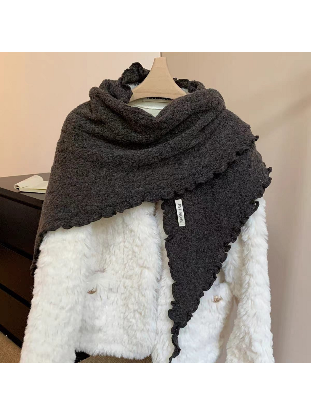 Gray knit scarf with scalloped edges draped over a white coat