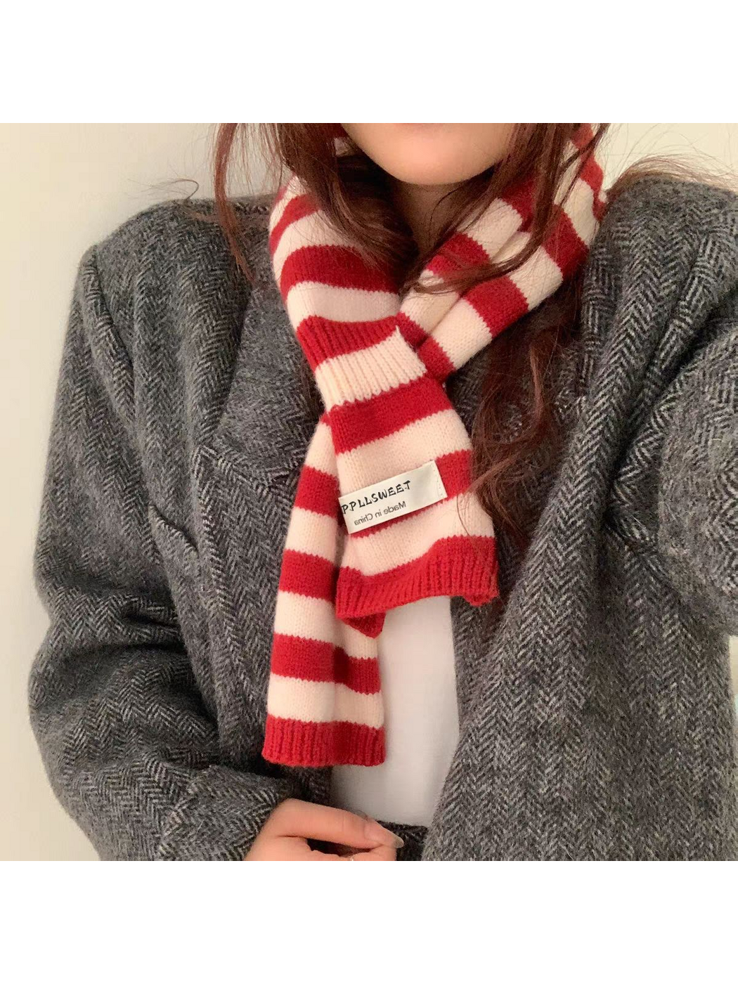Red striped knit scarf looped over a gray coat, showing ribbed ends