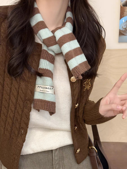 Mint striped knit scarf looped over a brown cardigan