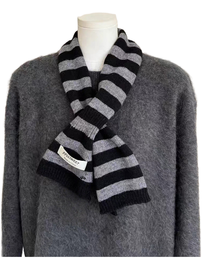 Gray striped knit scarf looped over a gray sweater on a mannequin