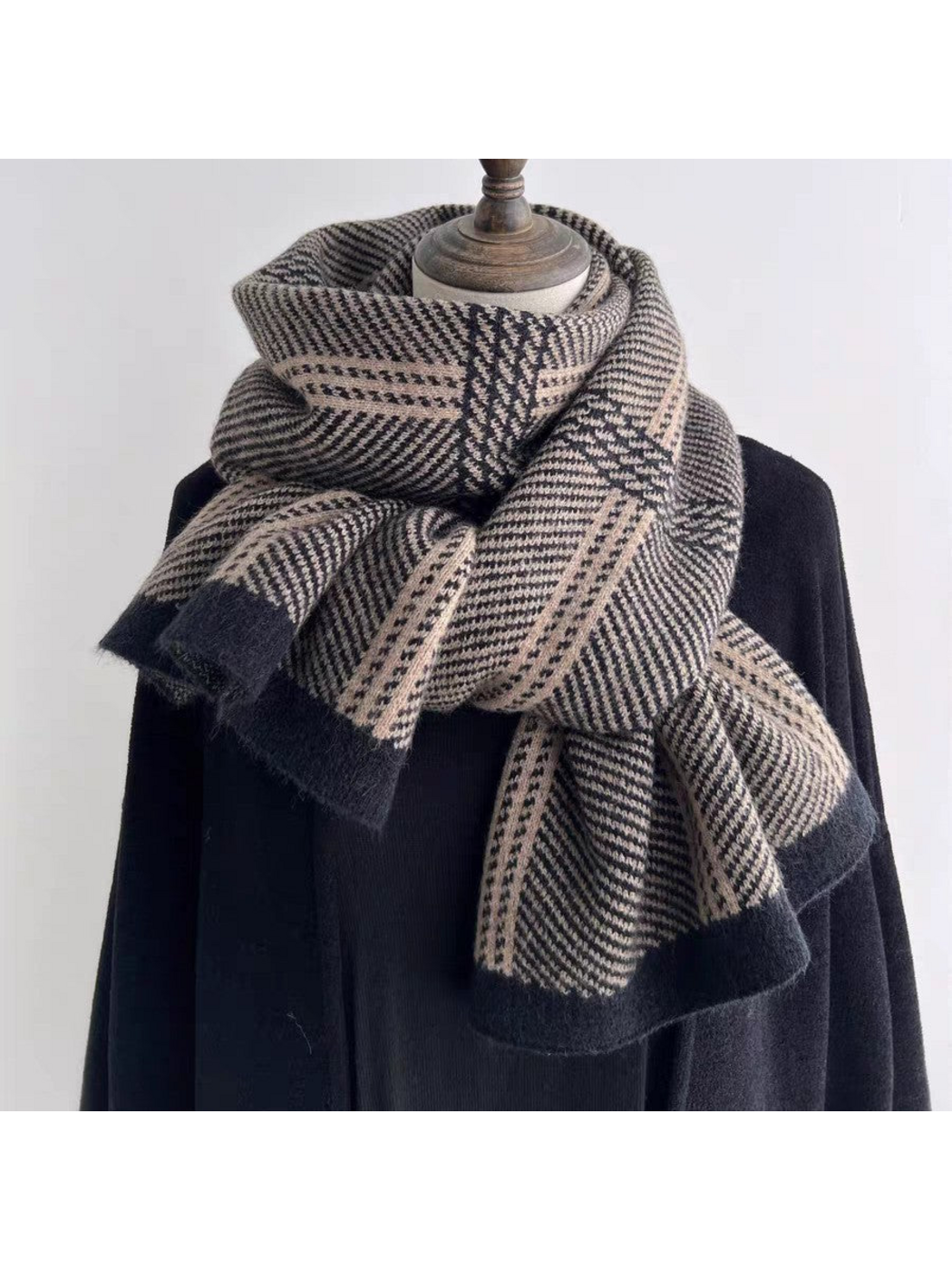 Black plaid scarf with contrasting borders, loosely knotted on a mannequin