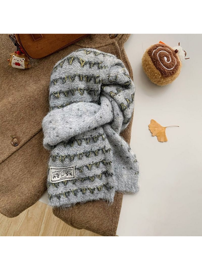 Gray knit scarf looped over a brown coat, with contrasting triangular bands