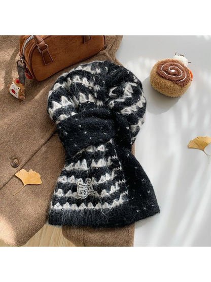Black knit scarf with ivory zigzag bands, looped over a brown coat