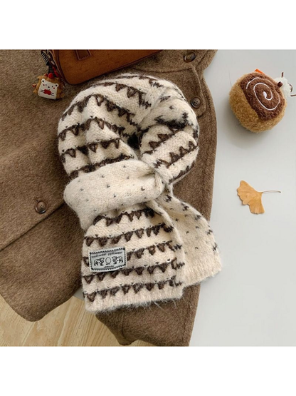 Ivory knit scarf with dark triangular bands and an elephant patch, looped over a coat