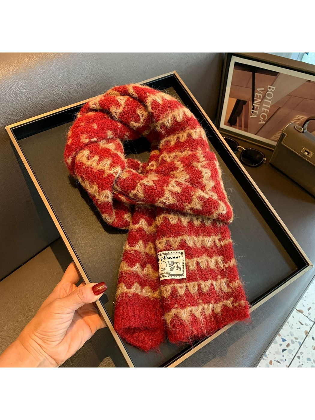Burgundy knit scarf looped on a tray, with contrasting zigzag bands and an elephant patch