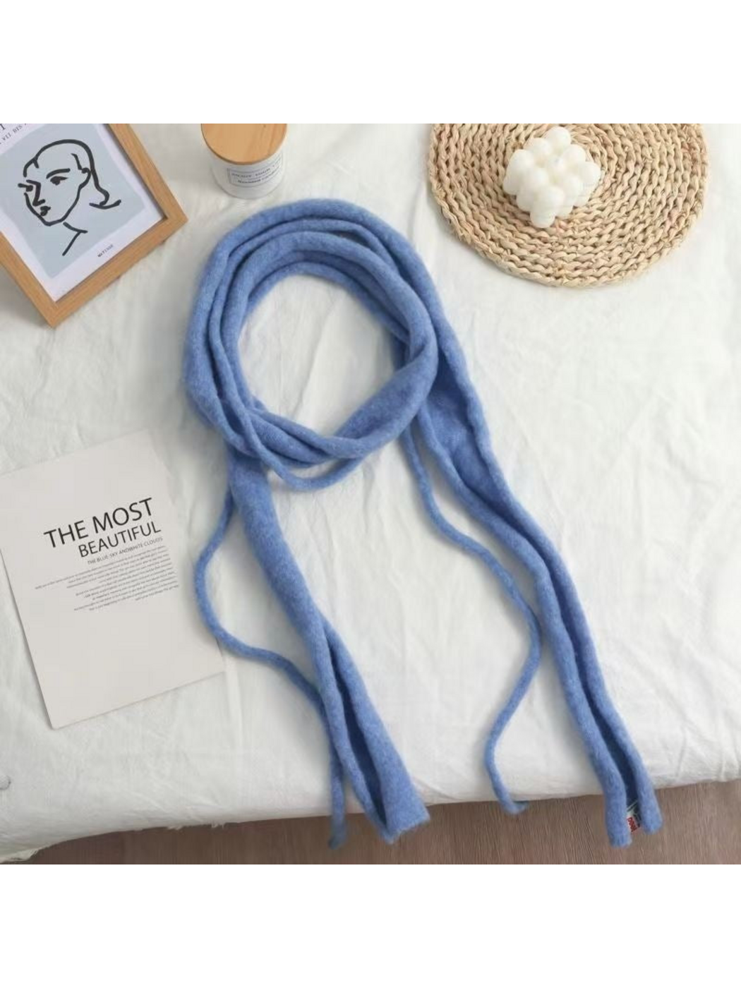 Blue fuzzy narrow scarf arranged in a loose loop with long hanging ends